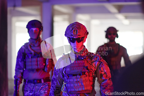 Image of Soldier squad team walking in urban environment colored lightis