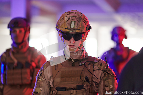 Image of Soldier squad team walking in urban environment colored lightis