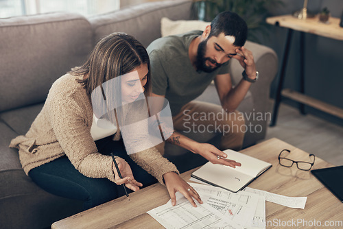 Image of It might be time for some debt relief. a young couple looking stressed while going over paperwork at home.