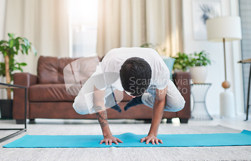 Image of Yoga transformed me mentally and physically. a handsome young man practising yoga in his living room at home.