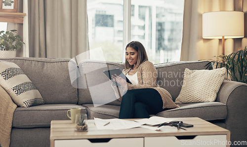Image of Budgeting is never a bore with apps like these. a young woman using a digital tablet while going through paperwork at home.
