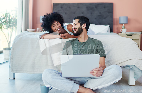 Image of Want to watch something. a man using his laptop while sitting in the bedroom with his girlfriend.