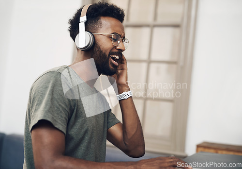 Image of Jamming to the beat of business. a young businessman using headphones while working in a modern office.