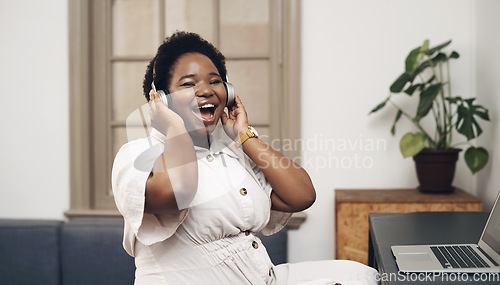 Image of The future superstar of design. a young businesswoman using headphones and a laptop in a modern office.