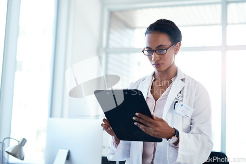 Image of Getting a detailed look at her patients symptoms. a young doctor going over paperwork in her consulting room.