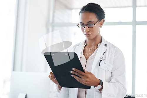 Image of These stats look good to me. a female young doctor recording a patients information on a clipboard.