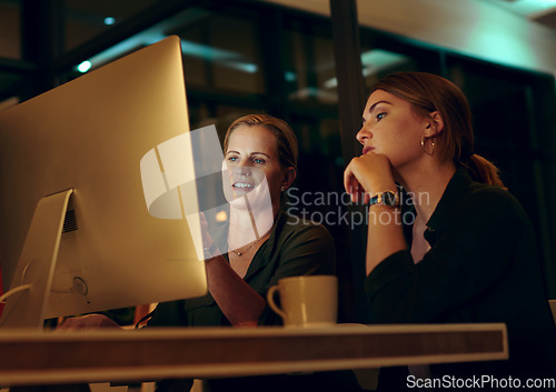 Image of Lets go over it one last time before shutting down. two businesswoman looking at something on a computer in an office at night.