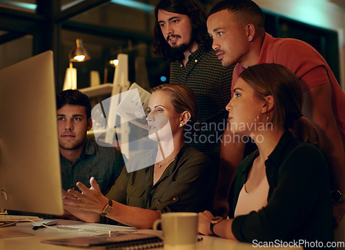Image of We never missed a deadline and were not starting now. a group of businesspeople looking at something on a computer in an office at night.