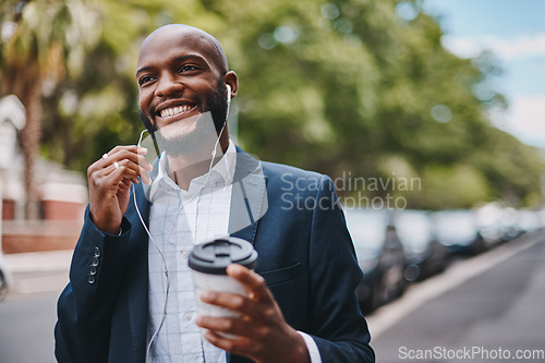 Image of This break is just what I needed to clear my head. a businessman holding a coffee and listening to music through earphones while walking through the city.