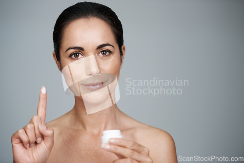 Image of Stay beautiful for longer. Cropped portrait of a beautiful mid adult woman showing the moisturizer she uses.