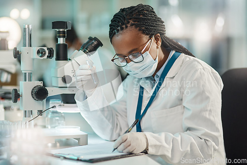 Image of Gathering information after careful observation. a young scientist writing notes while working in a lab.