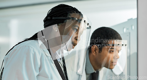 Image of Tracing back to the last detail. two scientists wearing face shields while working together in a lab.
