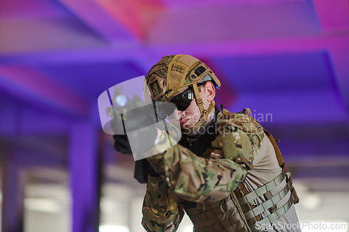 Image of A professional soldier undertakes a perilous mission in an abandoned building illuminated by neon blue and purple lights