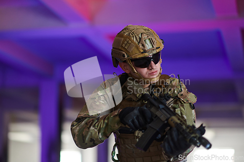 Image of A professional soldier undertakes a perilous mission in an abandoned building illuminated by neon blue and purple lights