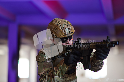 Image of A professional soldier undertakes a perilous mission in an abandoned building illuminated by neon blue and purple lights