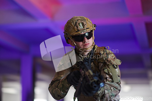 Image of A professional soldier undertakes a perilous mission in an abandoned building illuminated by neon blue and purple lights