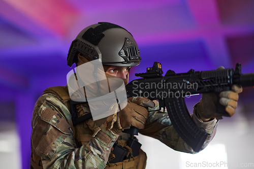 Image of A professional soldier undertakes a perilous mission in an abandoned building illuminated by neon blue and purple lights