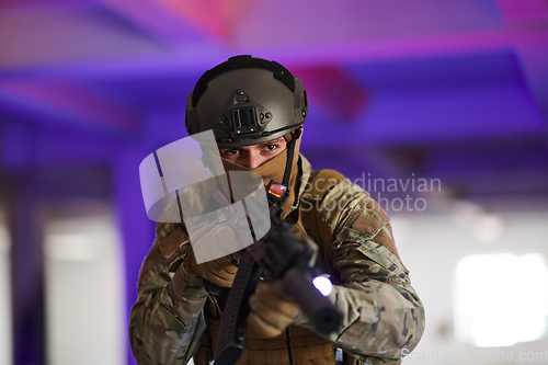 Image of A professional soldier undertakes a perilous mission in an abandoned building illuminated by neon blue and purple lights