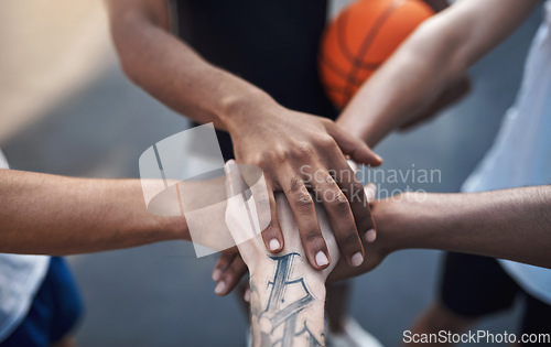 Image of Lets go team. Closeup shot of a group of sporty young men joining their hands together in a huddle on a sports court.