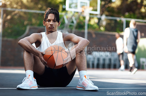 Image of A true champion believes in the impossible. Portrait of a sporty young man sitting on a basketball court.