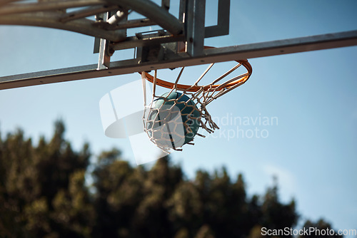 Image of Shooting hoop and scoring points. Closeup shot of a basketball landing into a net on a sports court.