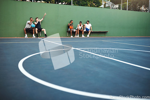 Image of Its break time. a group of sporty young men sitting on a basketball court.