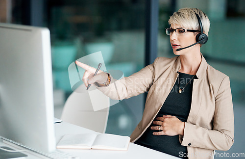 Image of Shell come up with a solution that works. a pregnant businesswoman wearing a headset while working on a computer in an office.