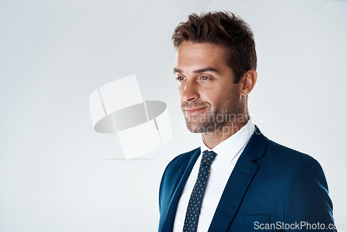 Image of Time to make the day great again. Studio shot of a confident young businessman wearing a suit while standing against a grey background.