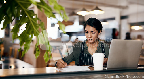 Image of The hard work behind a successful side hustle. a young woman using a laptop and going over paperwork while working in a cafe.