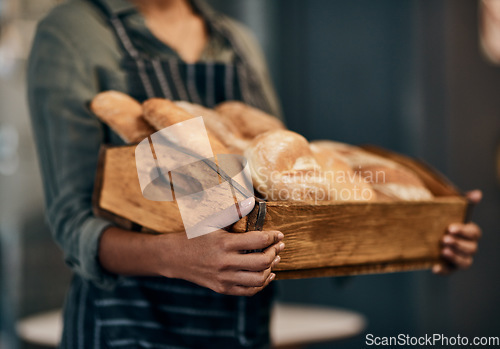 Image of Were the bread to your gravy. a woman holding a selection of freshly baked breads in her bakery.