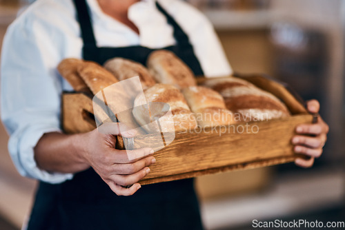 Image of Baked by the head baker herself. a woman holding a selection of freshly baked breads in her bakery.