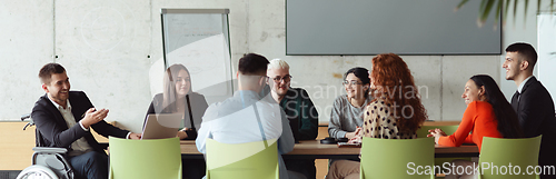 Image of Wide crop photo of a diverse group of business professionals, including an person with a disability, gathered at a modern office for a productive and inclusive meeting.