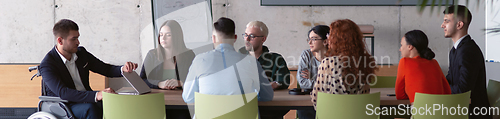 Image of Wide crop photo of a diverse group of business professionals, including an person with a disability, gathered at a modern office for a productive and inclusive meeting.