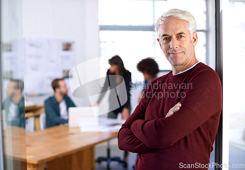 Image of A business hes proud of. Portrait of a mature male architect with his colleagues working in the background.