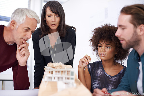 Image of Contemplating his teams design. a group of architects working together on building plans.