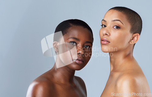 Image of Our hearts are in the right place. Portrait of two beautiful young women standing close to each other against a grey background.