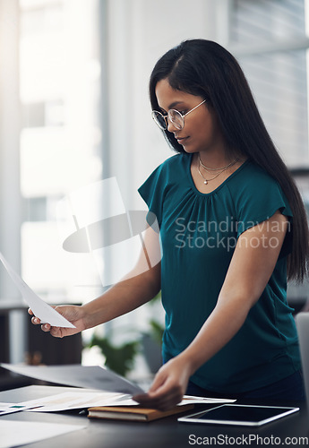 Image of Shes quite thorough when it comes to planning. a young businesswoman going through paperwork in an office.