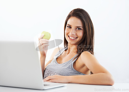 Image of Laptop, portrait and woman nutritionist with apple in studio for wellness, diet or eating plan on white background. Weight loss, face and female health influencer with blog survey, help or menu guide