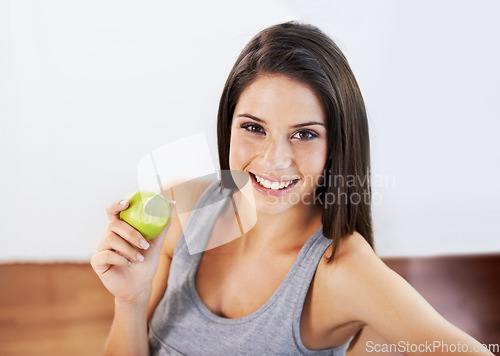Image of Portrait, smile and apple with a woman eating food for health, diet or nutrition in the kitchen of her home. Fruit, nutritionist and a happy young model in a house for organic wellness or weight loss