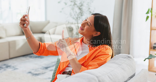 Image of Happy, selfie and woman on sofa in living room, home or relax in apartment with peace on social media and app. Influencer, smile and post happiness online of photography on couch in house lounge