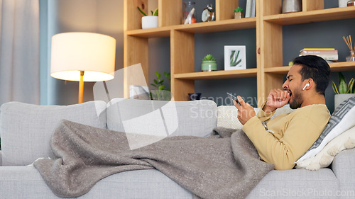 Image of Man, tired and yawn, smartphone and watch video or film with online streaming, relax on couch and playing games. Mobile app, subscription and fatigue, live streaming at home or tv show and sleepy