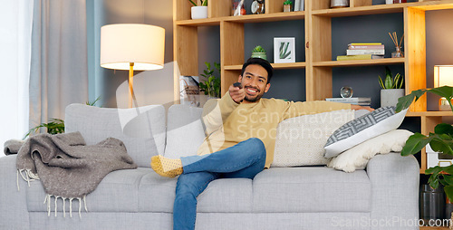Image of Watching tv, streaming and subscription with a man on a sofa in the living room of his home to relax. Television, video and remote with a young person changing the movie channel in his apartment