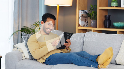 Image of Happy, relax and asian man with a tablet a sofa for social media, chat or streaming at home. Digital, app and Japanese male in a living room smile for gif, meme or web, post and online communication