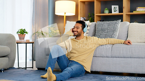 Image of Man, relax on living room floor and headphone, listening to music with audio streaming, happiness and tech at home. Chill at the weekend, wellness and podcast with sound, connectivity and radio