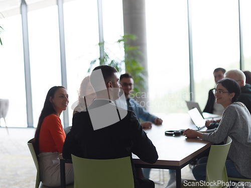 Image of A diverse group of business professionals, including an person with a disability, gathered at a modern office for a productive and inclusive meeting.