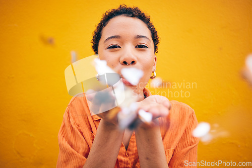 Image of Flowers, petals and portrait of woman on orange background for natural beauty, skincare and romance. Blowing, happy and female person with floral confetti for cosmetics, makeup and wellness in studio