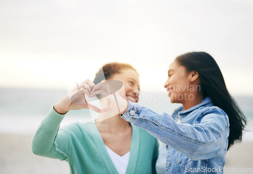 Image of Love, ocean and lesbian couple with heart hands on summer holiday adventure or sunset date together. Lgbt women, bonding and relax on ocean vacation with romance, pride and happy partner in nature.