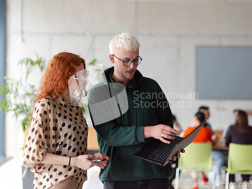 Image of In a modern and spacious office a team of business colleagues are seen diligently working together, using a laptop to analyze data and statistics