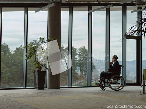 Image of A melancholic businessman in a wheelchair sitting with a sad expression, gazing through the window of a modern office, conveying a sense of solitude