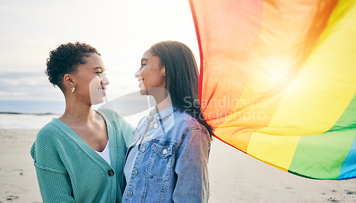 Image of Lesbian couple, pride flag and freedom hug at beach for romance, happy or care in nature. Rainbow, love and women at the ocean embrace lgbt, gay or partner pride, date or romantic relationship moment